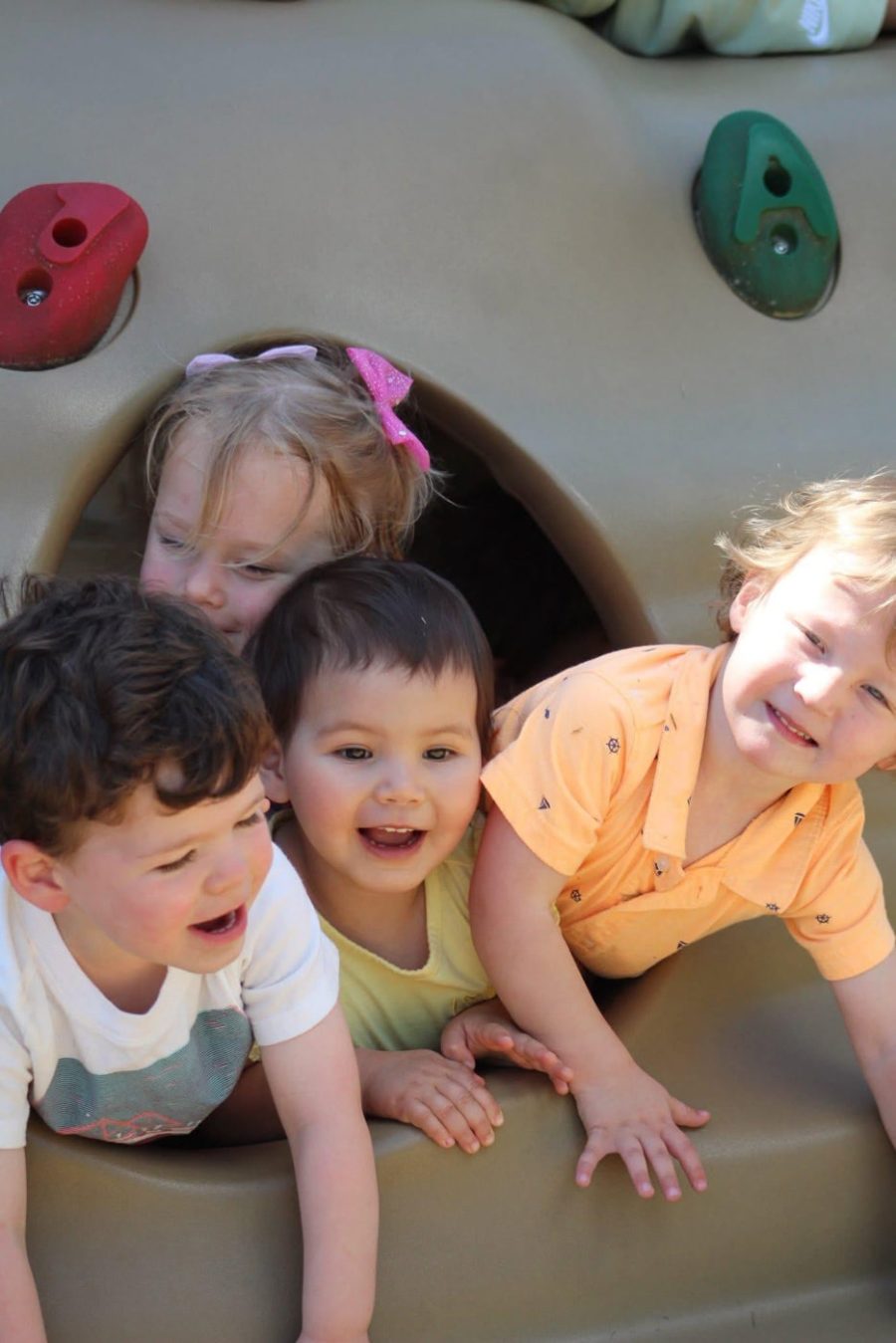 Three happy preschool children smiling together on a couch at The WEE Center