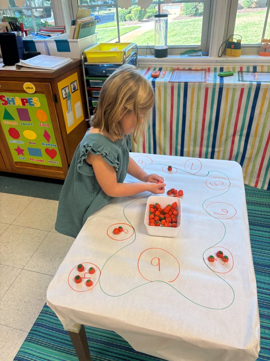 A preschool girl painting at a table in a WEE Center classroom