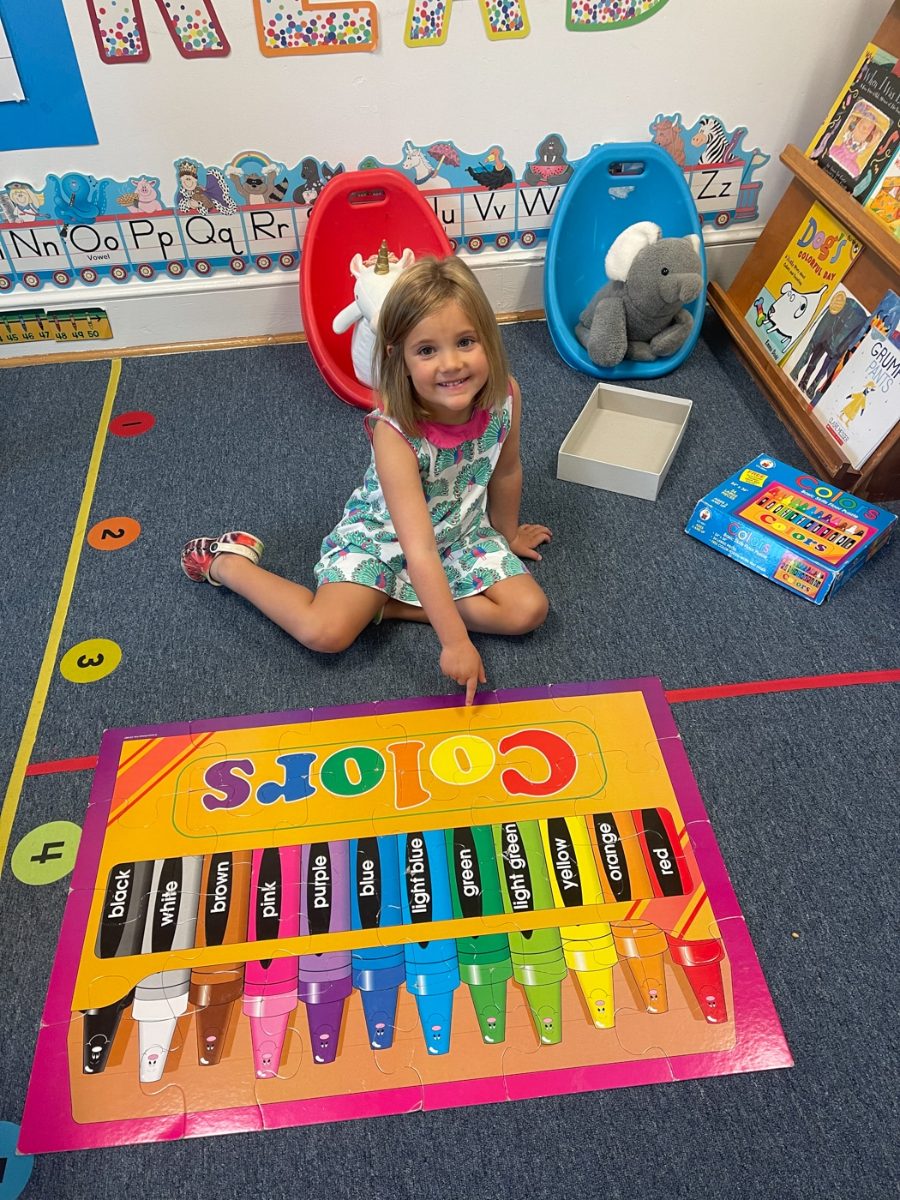 A preschool girl playing with a colors matching game on the classroom floor